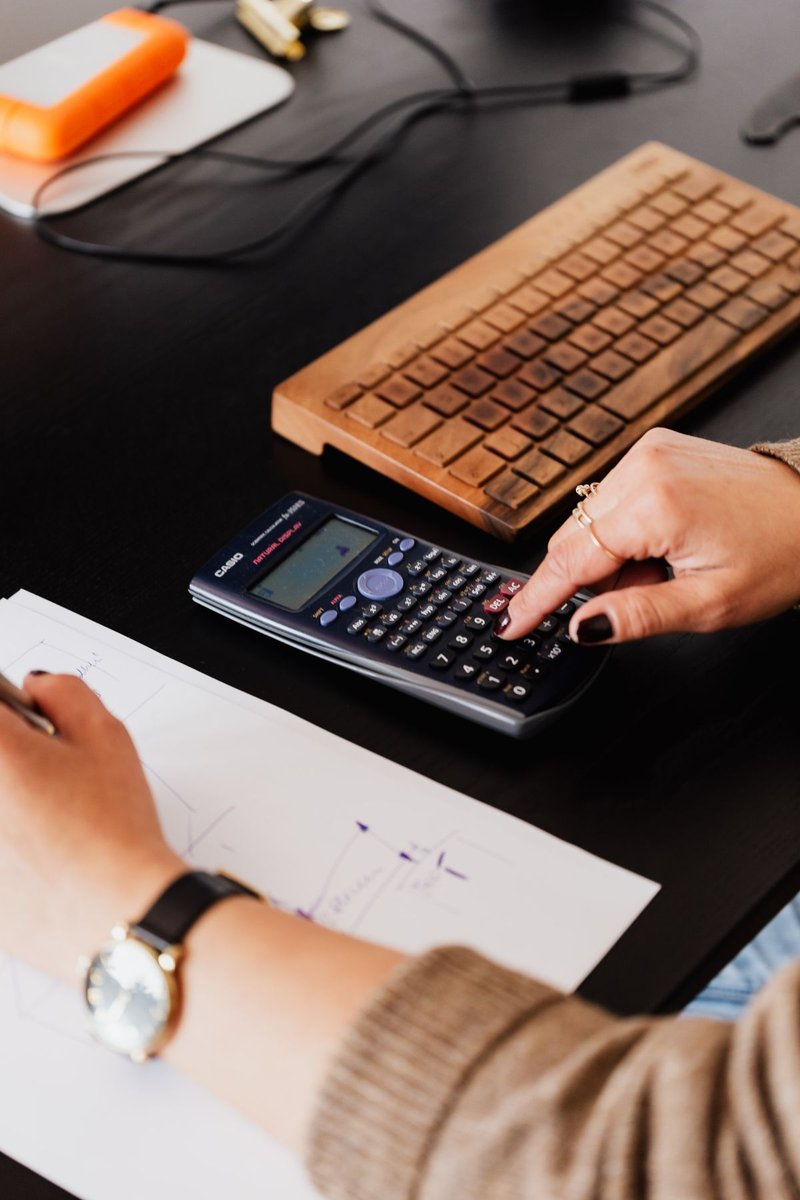 Bookkeeper writing figures on paper while using a calculator