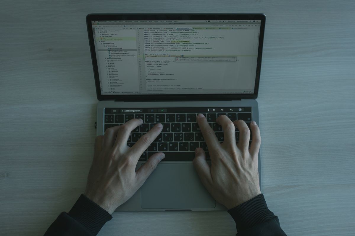 Overhead view of hands typing code in an IDE on a silver laptop